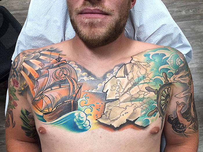 Man with a nautical-themed chest tattoo featuring a ship, map, and waves, showcasing incredible chest tattoo ideas.