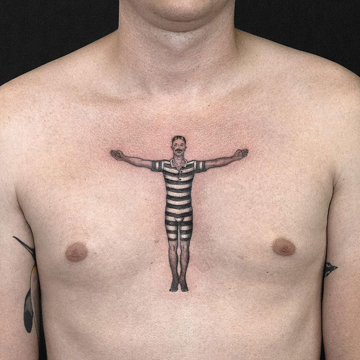Chest tattoo of a man in a striped suit, arms outstretched.
