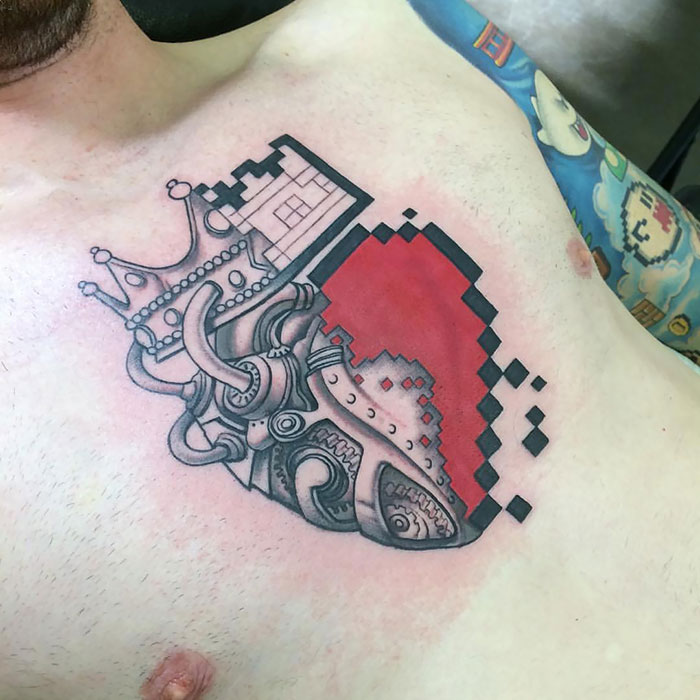 Creative chest tattoo featuring a mechanical heart design with pixelated elements and a crown.