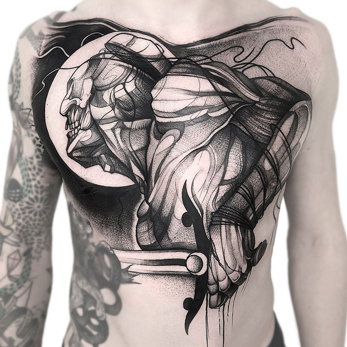 Abstract black ink chest tattoo design featuring a dynamic, skeletal figure with intricate shading and detail.