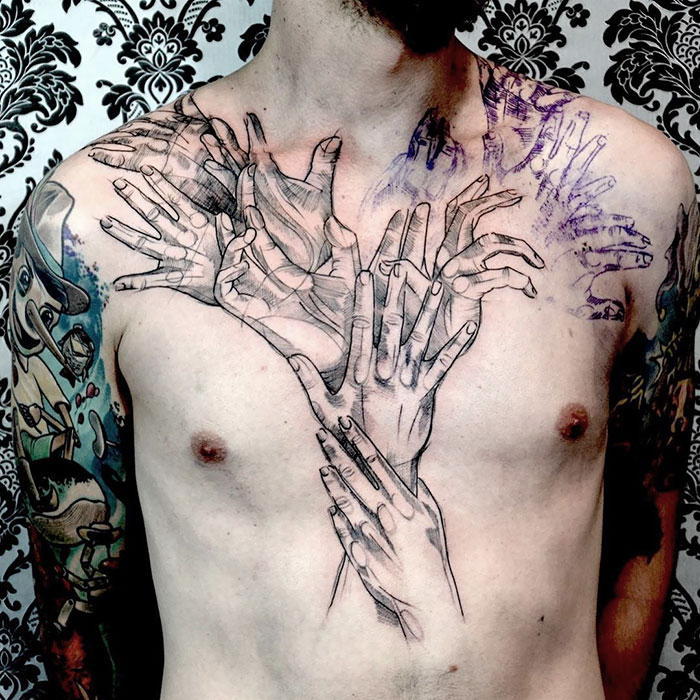 Chest tattoo of overlapping hands, showcasing incredible ink design on a man's upper body.