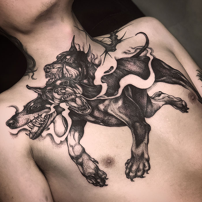 Three-headed dog tattoo on chest with intricate detailing, showcasing an incredible chest tattoo idea.