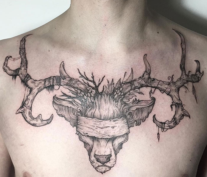 Intricate chest tattoo of a blindfolded deer head with detailed antlers.