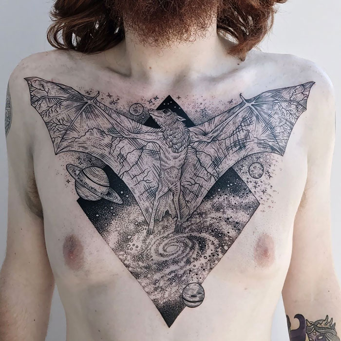 Incredible chest tattoo of a bat with cosmic elements, showcasing intricate ink art.