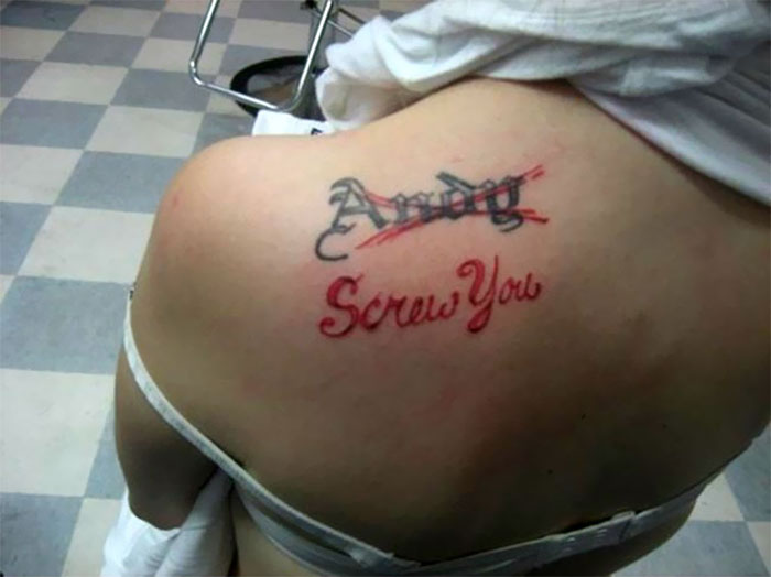 Tattoo of an ex's name covered with the words "S***w You" on a person's shoulder in a tattoo parlor.