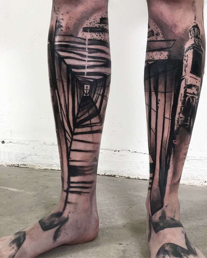 Abstract leg sleeve tattoo in black and gray tones, featuring geometric patterns and bold lines.