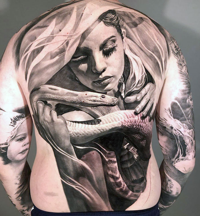 Detailed back tattoo featuring a woman with a snake, showcasing an impressive masterpiece.
