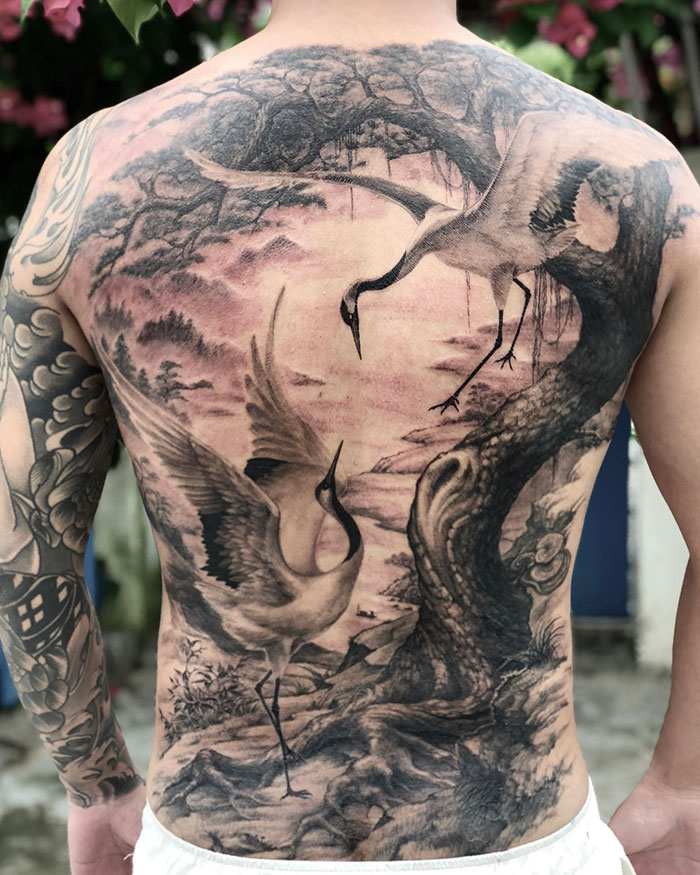 Intricate back tattoo featuring birds in a natural setting, showcasing impressive tattoo artistry.