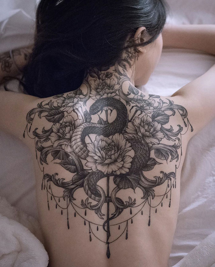A detailed snake and floral back tattoo, showcasing intricate artistry and craftsmanship.