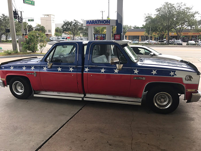 Funny car with double cab and patriotic paint at a Marathon gas station.