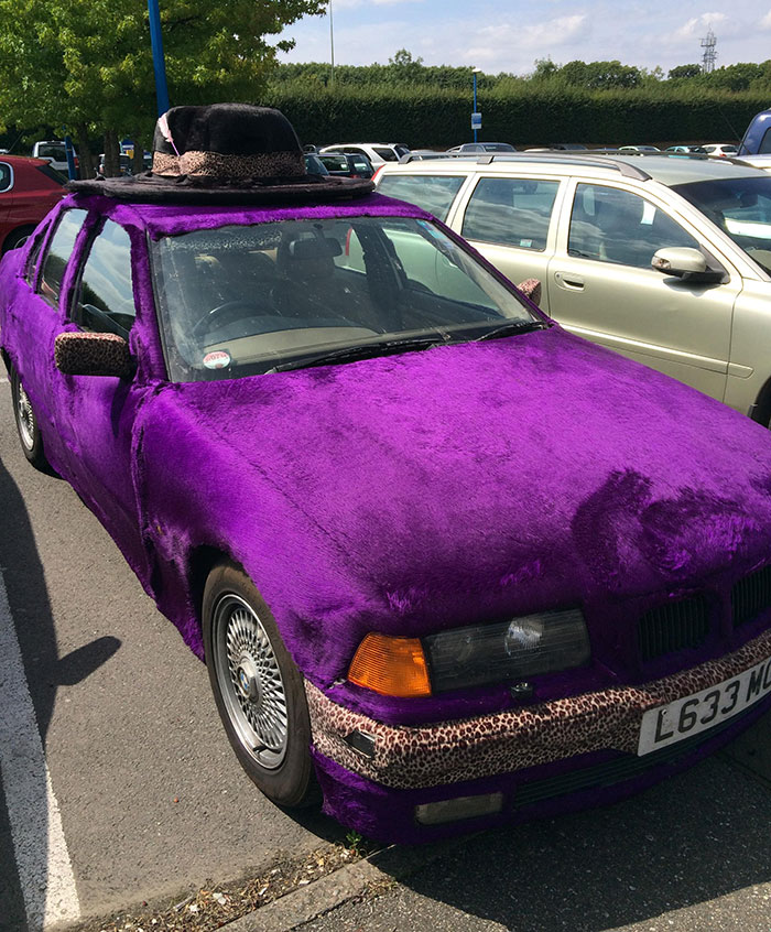 Funny car covered in purple fur with a leopard-print hat spotted in a parking lot.