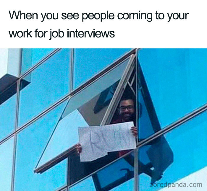 Person holding a "RUN" sign from an open window, humorously reacting to job interviews.