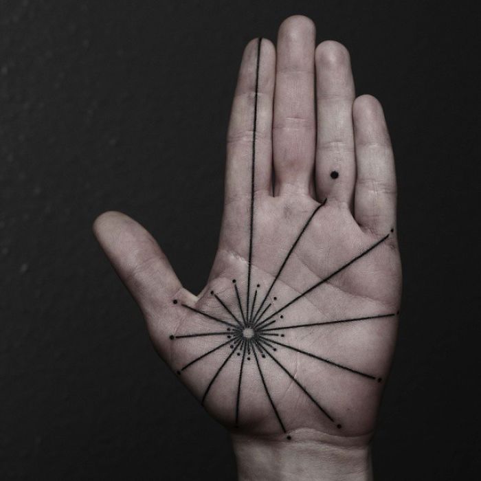 Intricate geometric palm tattoo design with fine lines and dots on a hand.