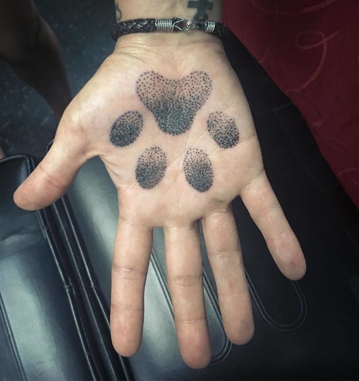 Hand with a paw print palm tattoo, a creative example of best palm tattoos.