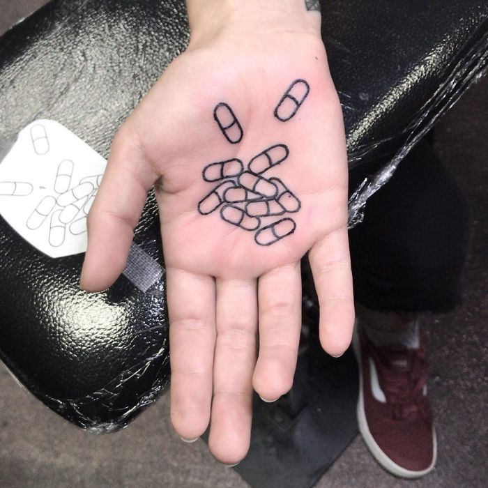 Palm tattoo featuring abstract capsule design on an open hand, showcasing creative ink art.