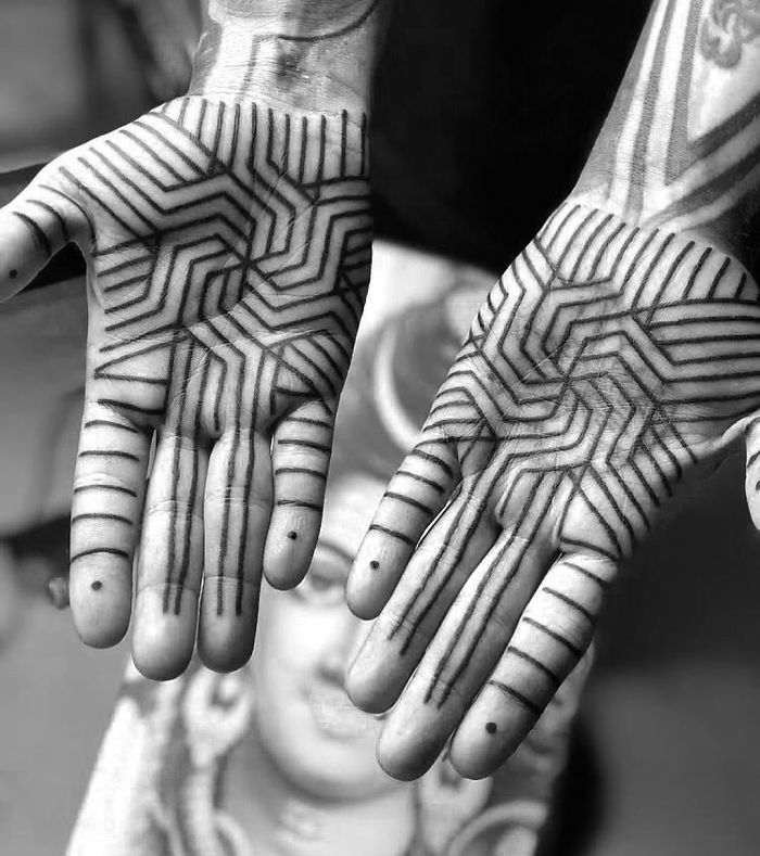 Geometric palm tattoos with intricate line patterns on both hands.