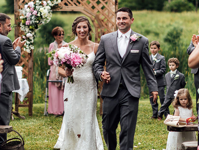 Bride and groom walking outdoors as groom’s family releases butterflies during wedding to honor his sister who died. Bride and groom walking outdoors as groom’s family releases butterflies during wedding to honor his sister who died.
