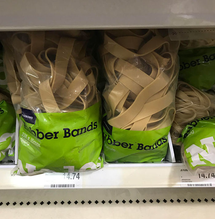 Bundles of rubber bands in green packaging resembling uncooked fettuccine pasta in a store display shelf.