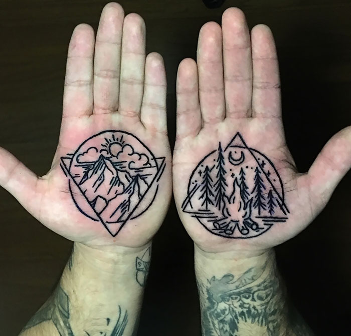 Intricate palm tattoos featuring mountain and forest designs on hands.