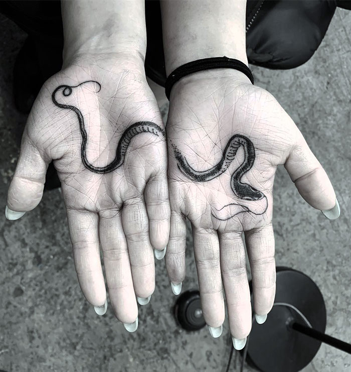 Hands displaying a snake design palm tattoo.