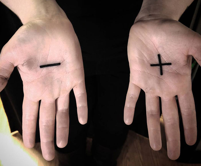 Hands with palm tattoos featuring a minus and plus sign, highlighting unique palm tattoo designs.