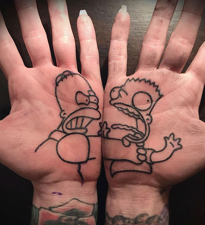 Palm tattoos featuring stylized cartoon characters Homer and Bart confronting each other across both hands.