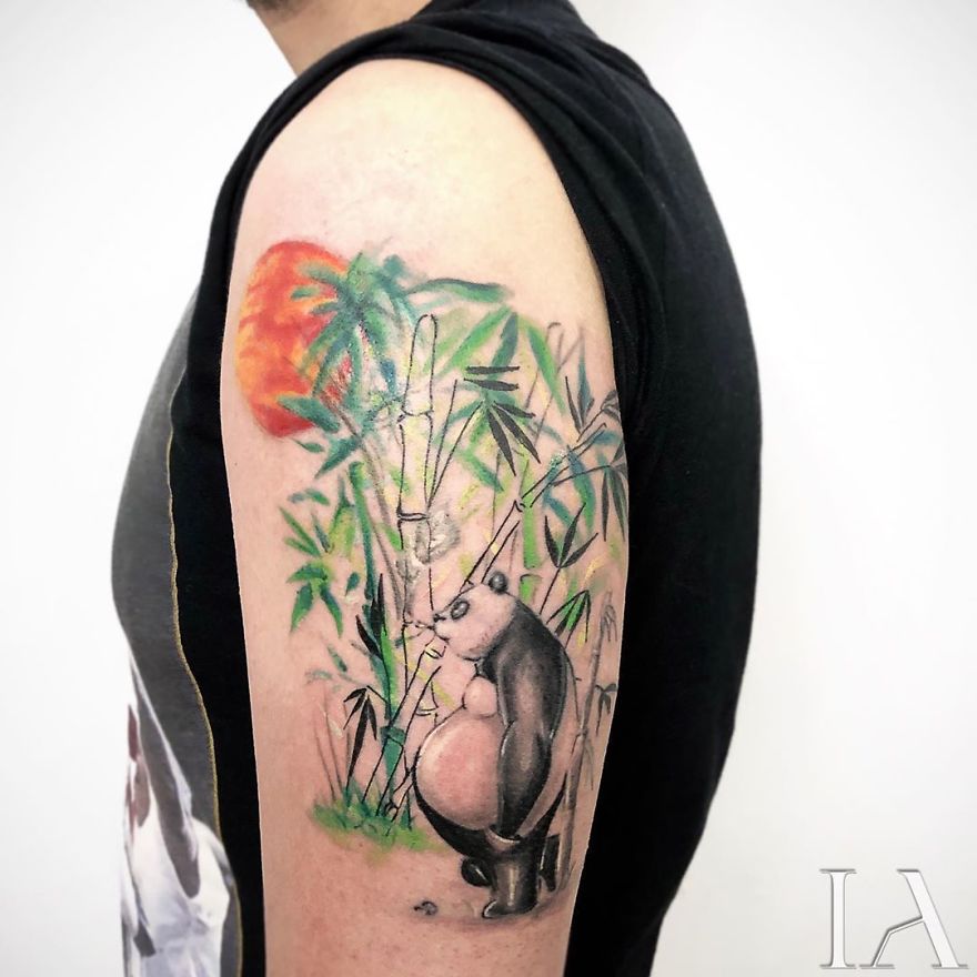 Panda tattoo on upper arm with bamboo and sun, created by a Turkish tattoo artist.