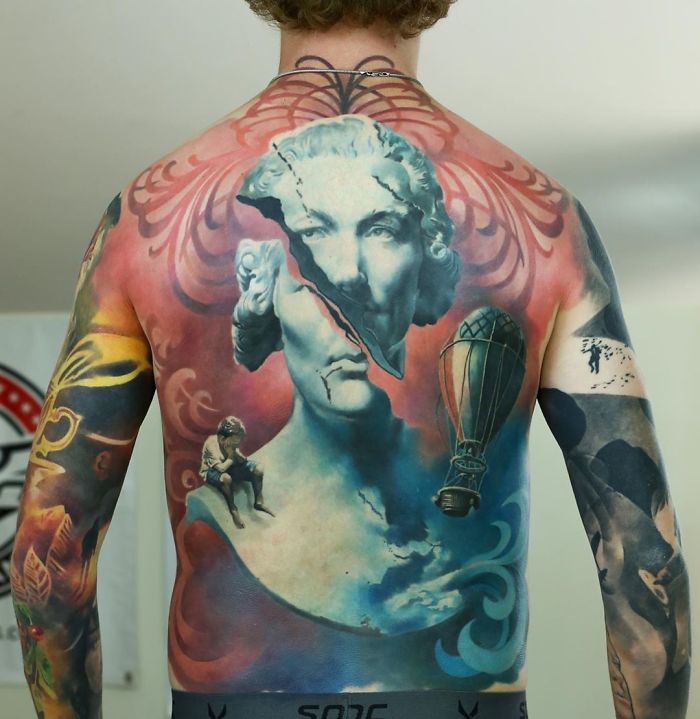 Colorful back tattoo featuring a bust and hot air balloon, exemplifying impressive back tattoos as masterpieces.