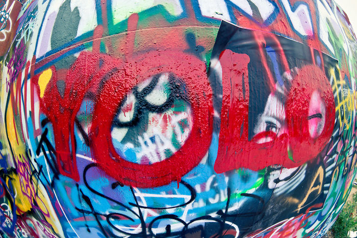 Colorful graffiti wall featuring bold red text on a YOLO theme reflecting forgotten hottest trends from the past decade.