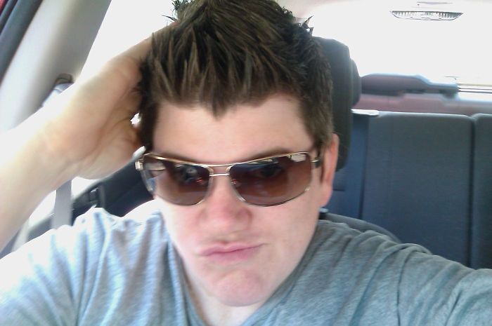 Young man with spiked hair and sunglasses in a car, embodying one of the hottest trends from the past decade forgotten by many.