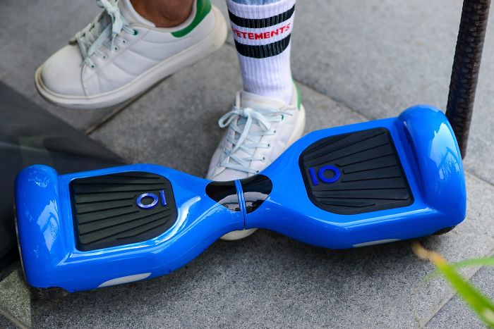 Blue hoverboard on pavement near person wearing white sneakers and socks, showcasing popular trends from the past decade forgotten by many.