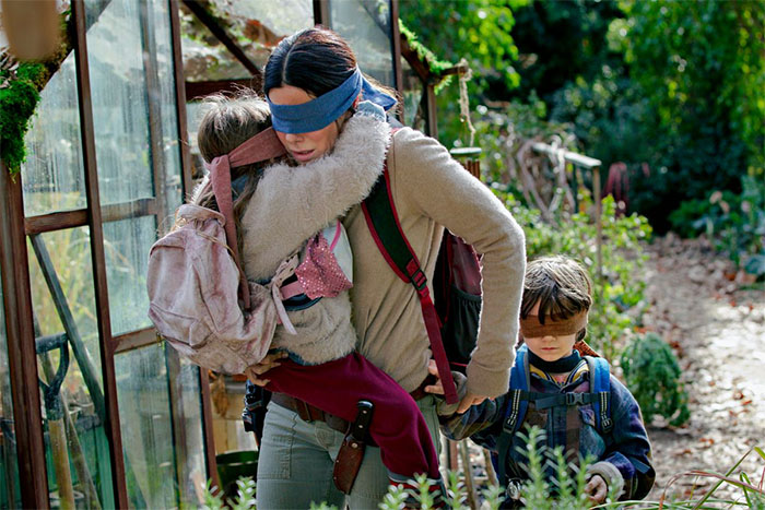 Woman and children wearing blindfolds while walking outdoors, illustrating the hottest trends from the past decade concept.