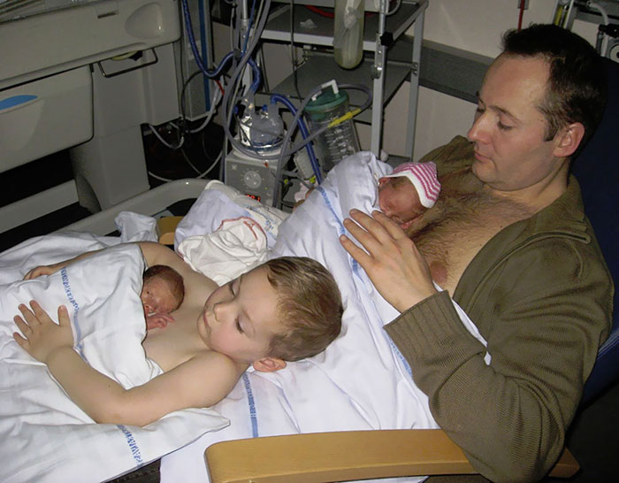 A Big Brother Helps His Father Give Skin To Skin Contact To His Premature Twin Siblings