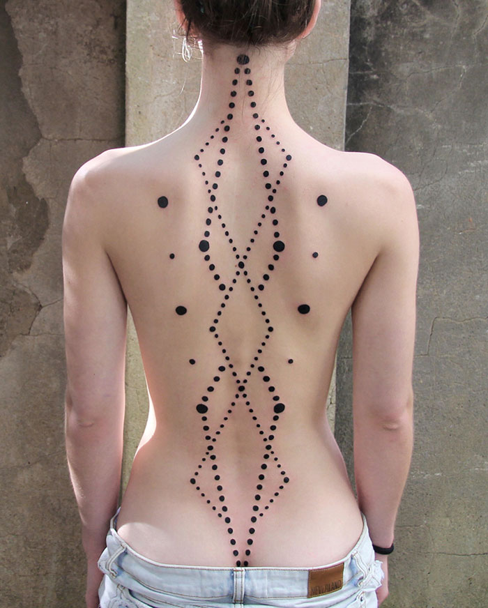 Intricate symmetrical back tattoo design featuring dot patterns.