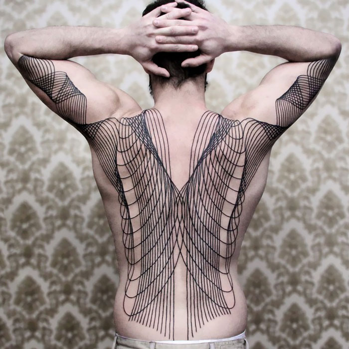 Intricate geometric back tattoo, showcasing impressive art on a man's back with arms raised against a patterned background.