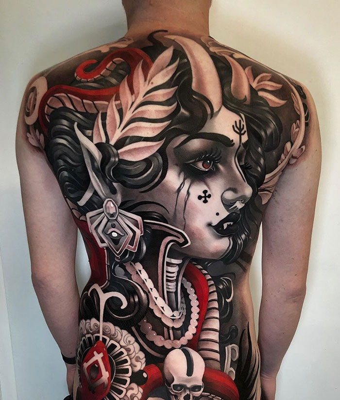 Intricate back tattoo featuring a detailed portrait of an elf with horns and elaborate designs.