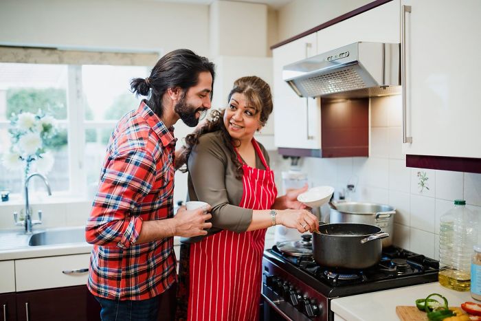 Middle-aged woman cooking in kitchen with young man, illustrating age young people leave parents home in different countries. Middle-aged woman cooking in kitchen with young man, illustrating age young people leave parents home in different countries.