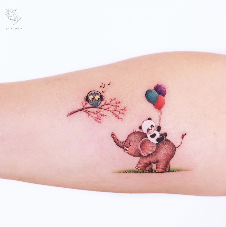 Tattoo design of a panda on an elephant with balloons, next to a singing bird on a branch, on human skin.