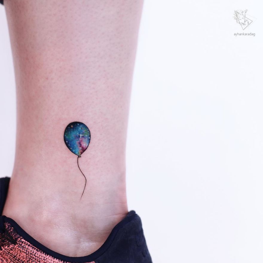 Colorful balloon tattoo on skin with galaxy pattern.