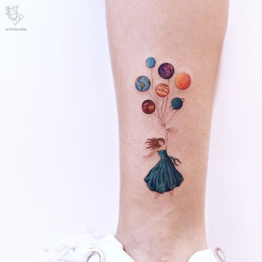 Colorful tattoo design of a girl in a dress holding planet balloons on human skin.
