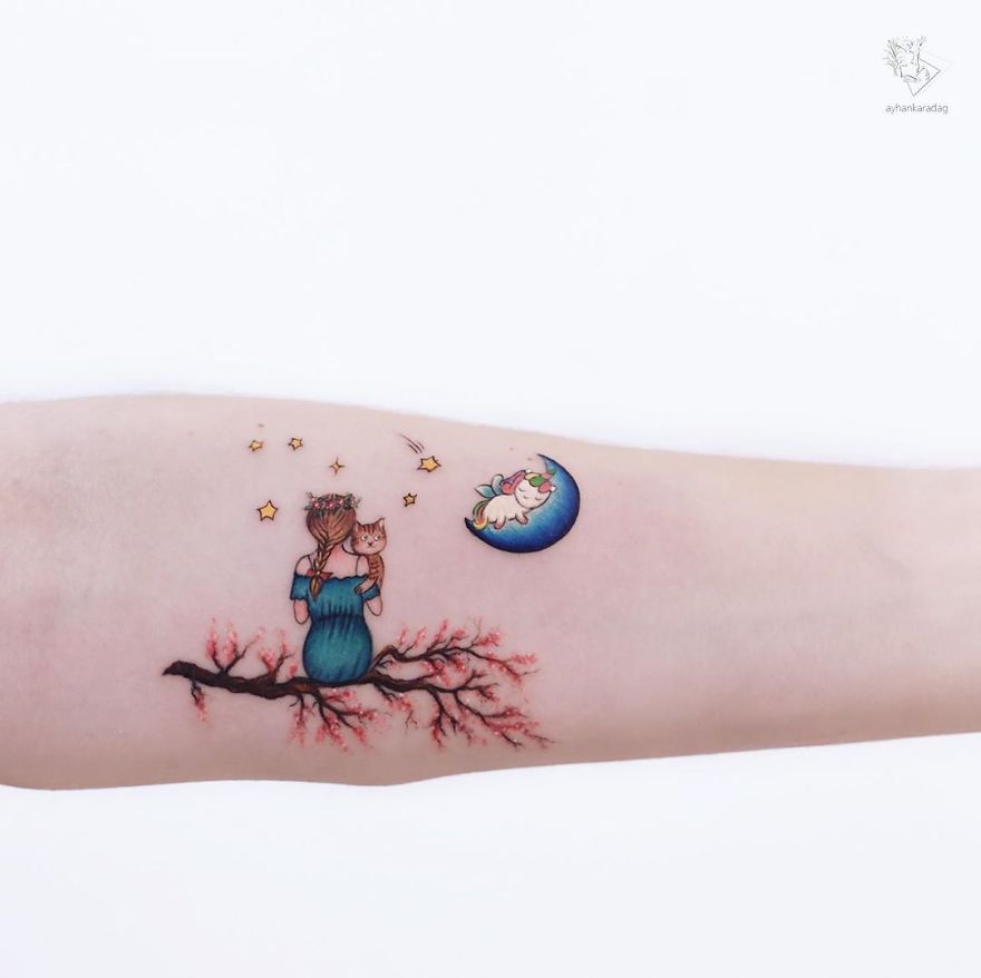 Tattoo of a girl and cat sitting on a branch under stars and moon on human skin.