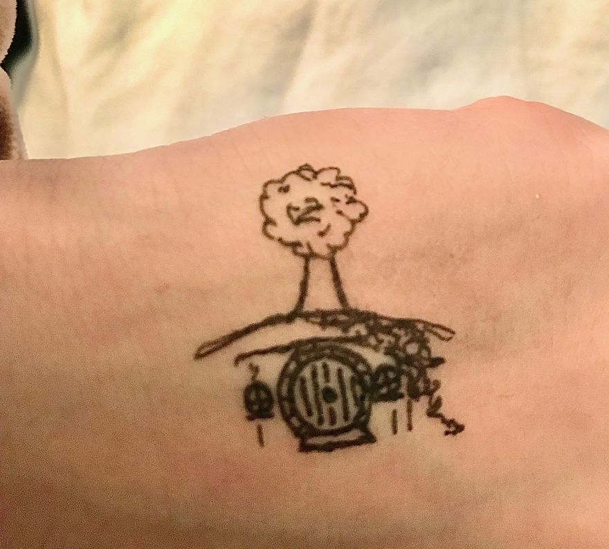 Hand-drawn Tolkien-inspired 'tattoo' on skin, featuring a tree and round door design.