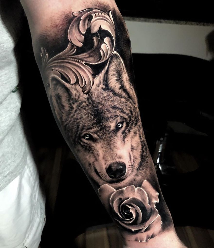Masculine tattoo featuring a detailed wolf face and rose design on an arm.