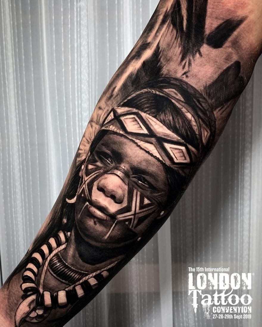 Masculine tattoo of a tribal face on a forearm, showcased at the London Tattoo Convention 2019.