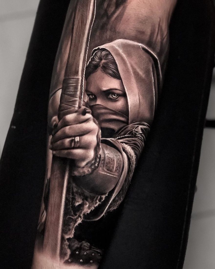 Tattoo of a hooded archer with intense gaze, exemplifying masculine tattoo art.