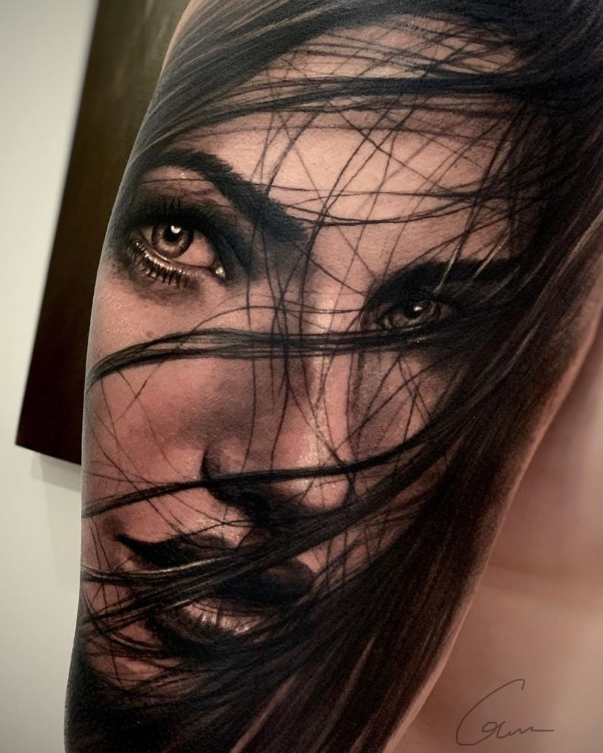 Realistic tattoo of a woman's face with hair across her eyes, showcasing masculine art style of 2019.