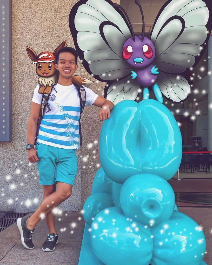 Person posing with Pokémon illustrations, including Eevee and Butterfree, next to a blue sculpture.