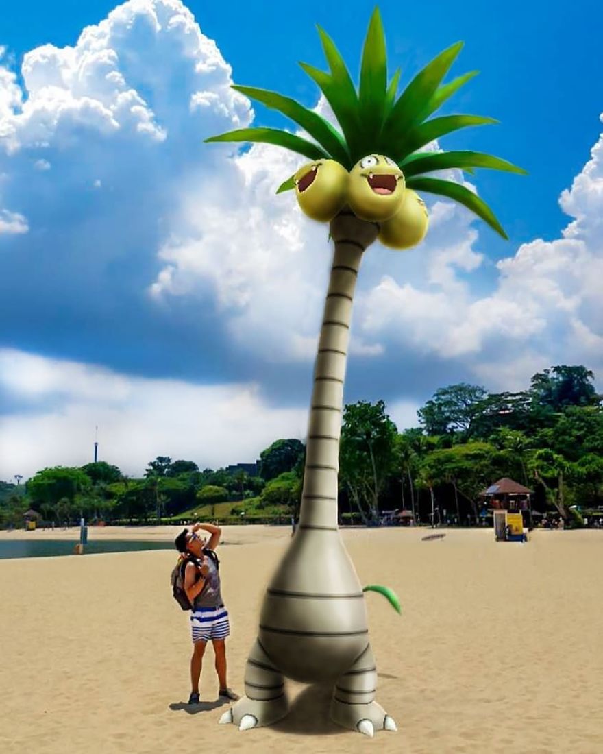 Man on beach interacting with tall Pokémon illustration under a blue sky.