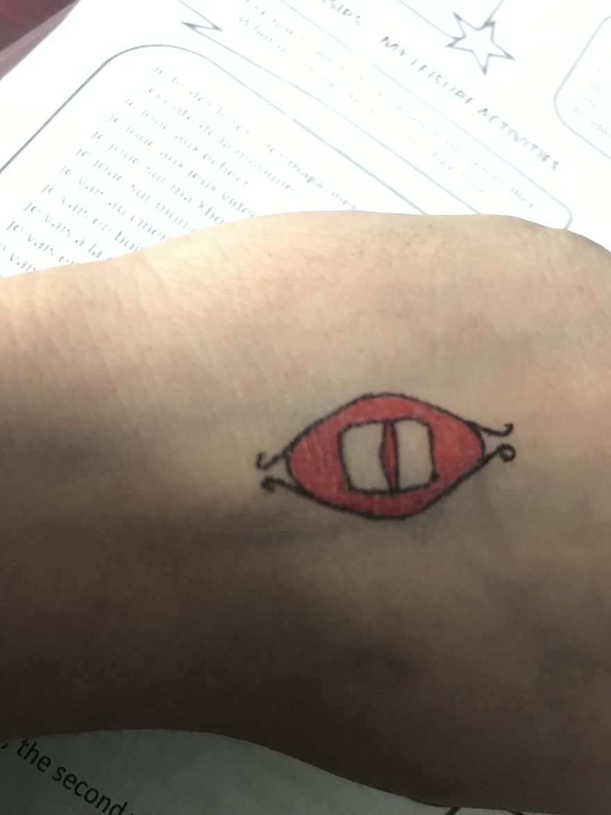 Hand-drawn eye tattoo inspired by J. R. R. Tolkien, drawn on skin over a school worksheet.