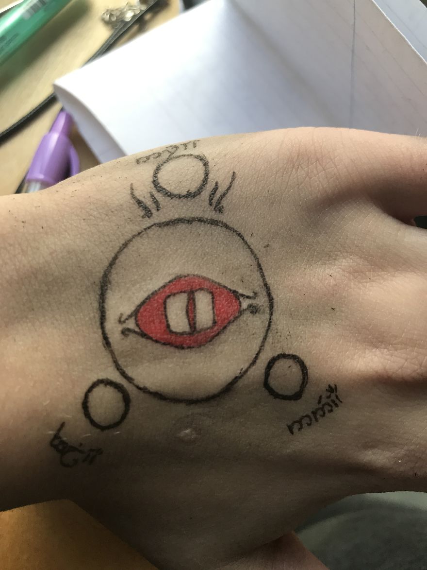Hand-drawn J. R. R. Tolkien inspired tattoo sketch on a hand, featuring an eye and script symbols.